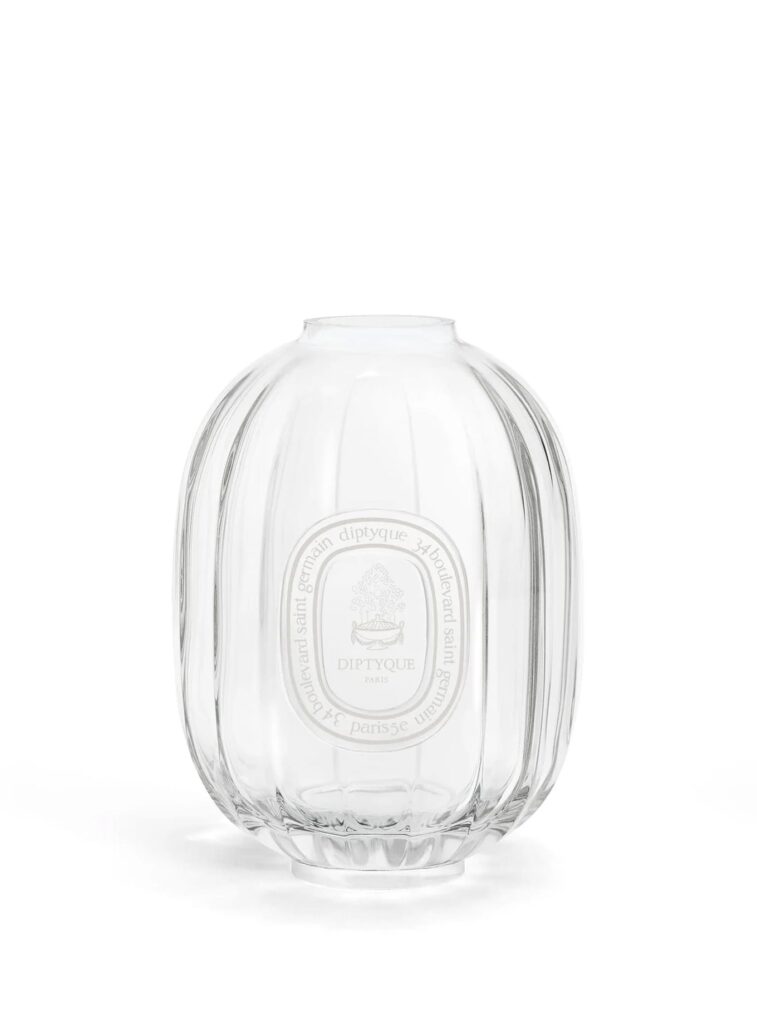 Vaso de cristal Diptyque para difusor de fragancia, diseño transparente acanalado con emblema blanco en el frontal.