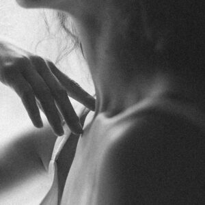 Mano acariciando el hombro en escena sensorial, imagen conceptual sobre el uso del perfume sobre la piel