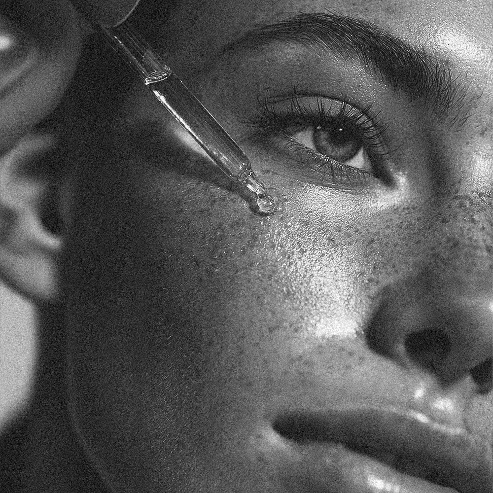 Primer plano de un sérum facial aplicado con gotero sobre la piel del rostro, mostrando textura y luminosidad en una rutina de skincare.