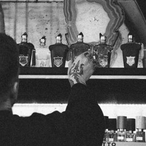 Persona observando perfumes en estantería, comparación entre perfumería nicho y perfume comercial